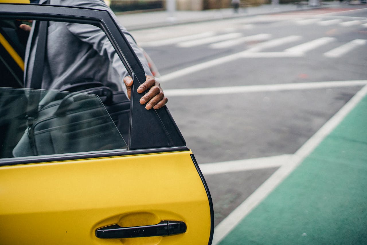 Close-up of hand on taxi door in city street, capturing urban mobility.