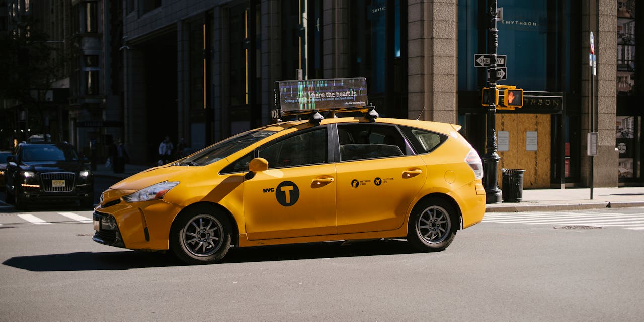 A yellow NYC taxi car waiting at the intersection on a sunny day.